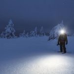 Trekker with a headlamp walking in a snowy Riisitunturi National