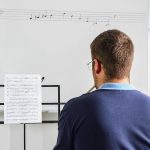 Young student studies lesson on sheet music in the classroom.