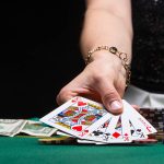Girl plays poker in a casino, with chips, dollars, and wine. Con